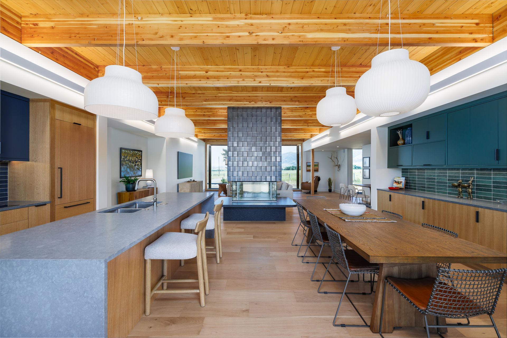 Modern kitchen with wood ceiling, blue cabinets, large island, and pendant lights