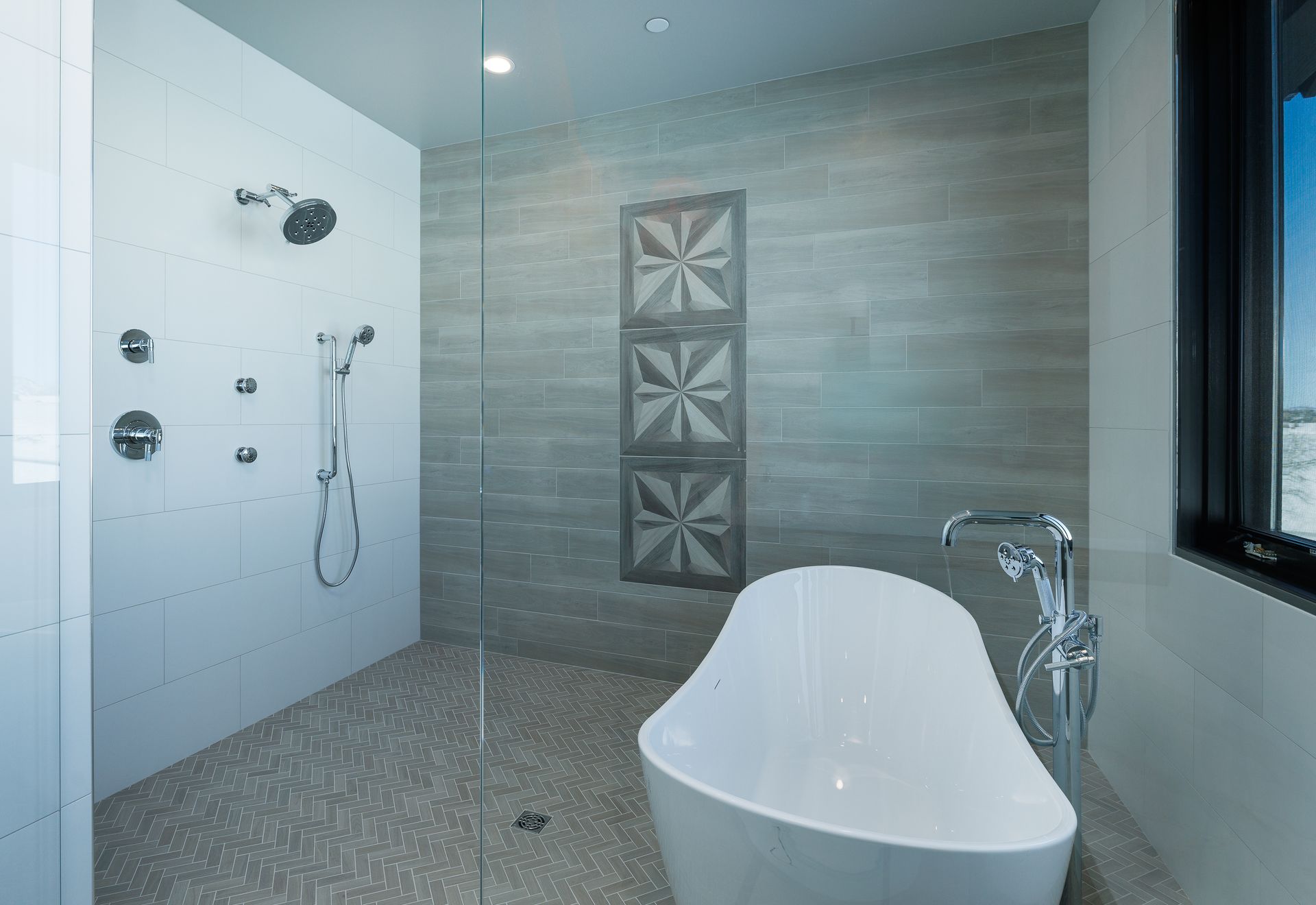 Modern bathroom with a freestanding tub, walk-in shower, and gray tiled walls