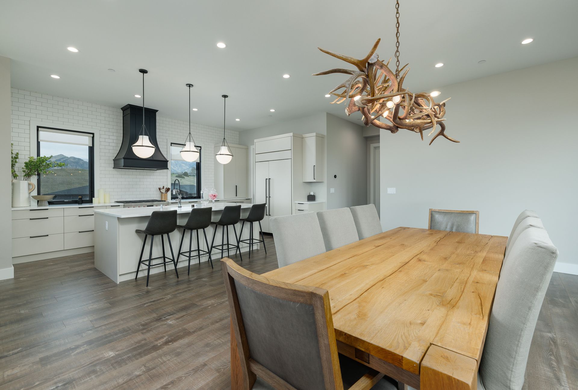 Modern open-plan kitchen and dining room with white cabinets, large island, and rustic wood table