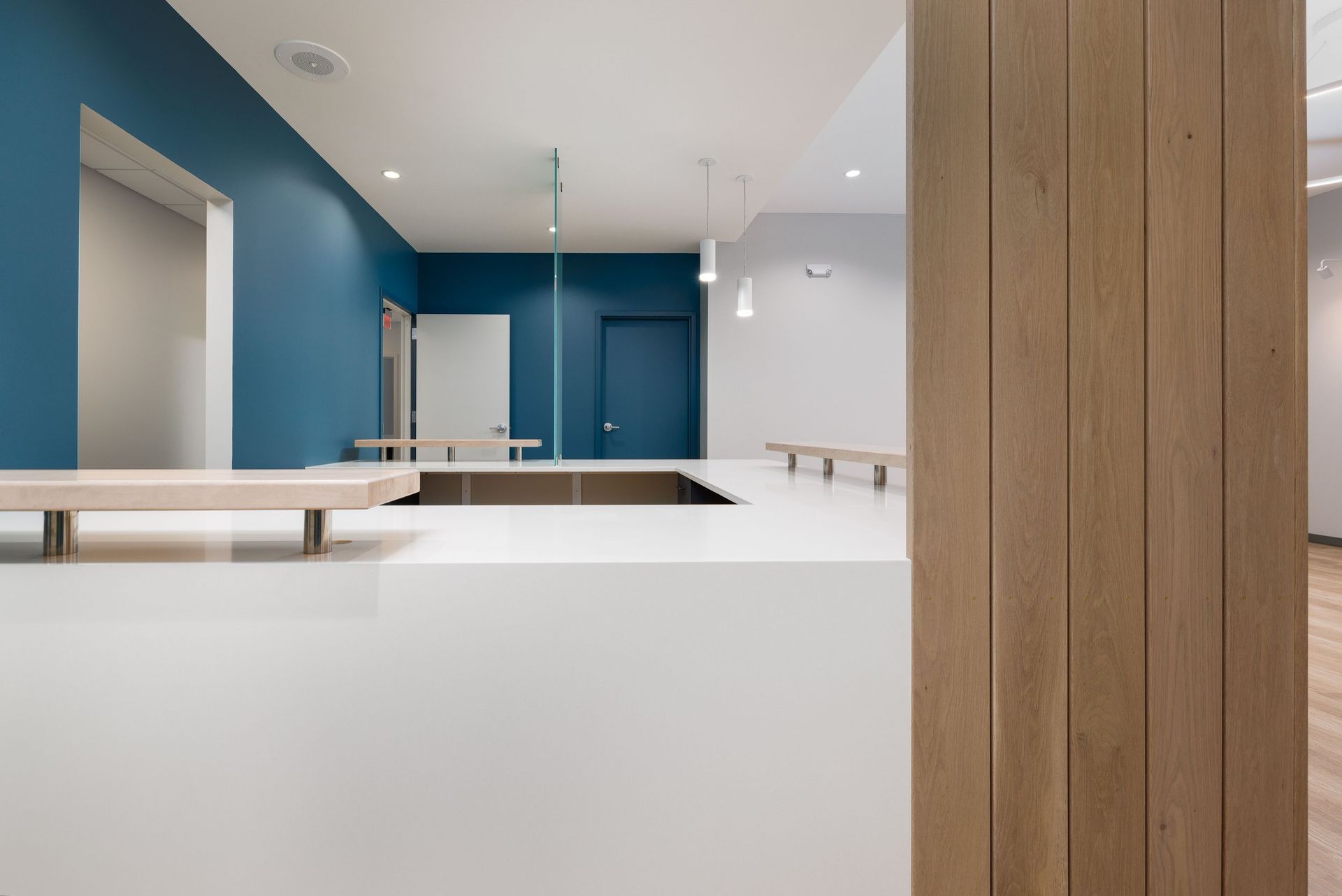 A reception desk with a white counter and wooden column in a modern interior with blue and white walls.