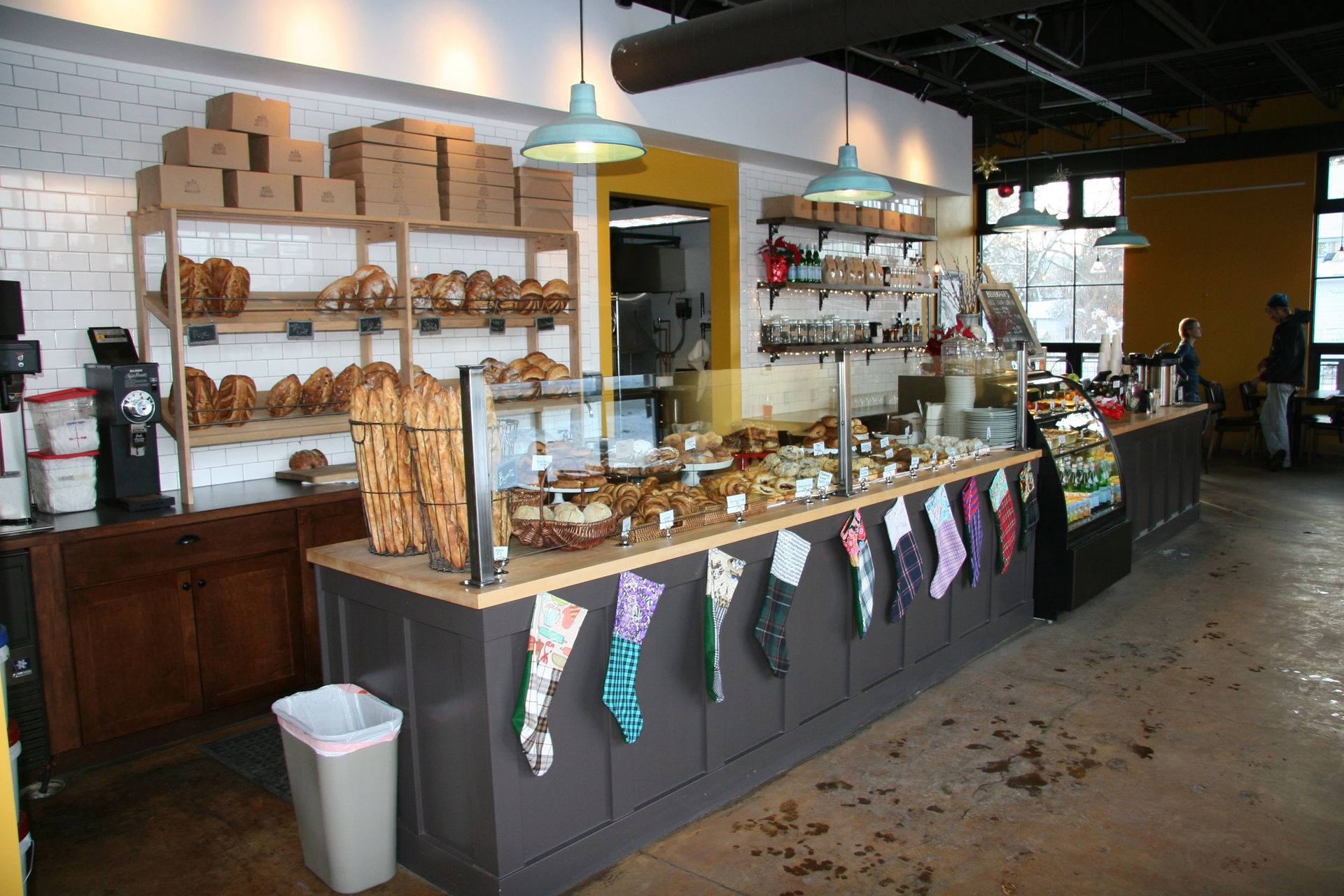 A bakery counter with shelves of bread and festive stockings hanging from the front edge.
