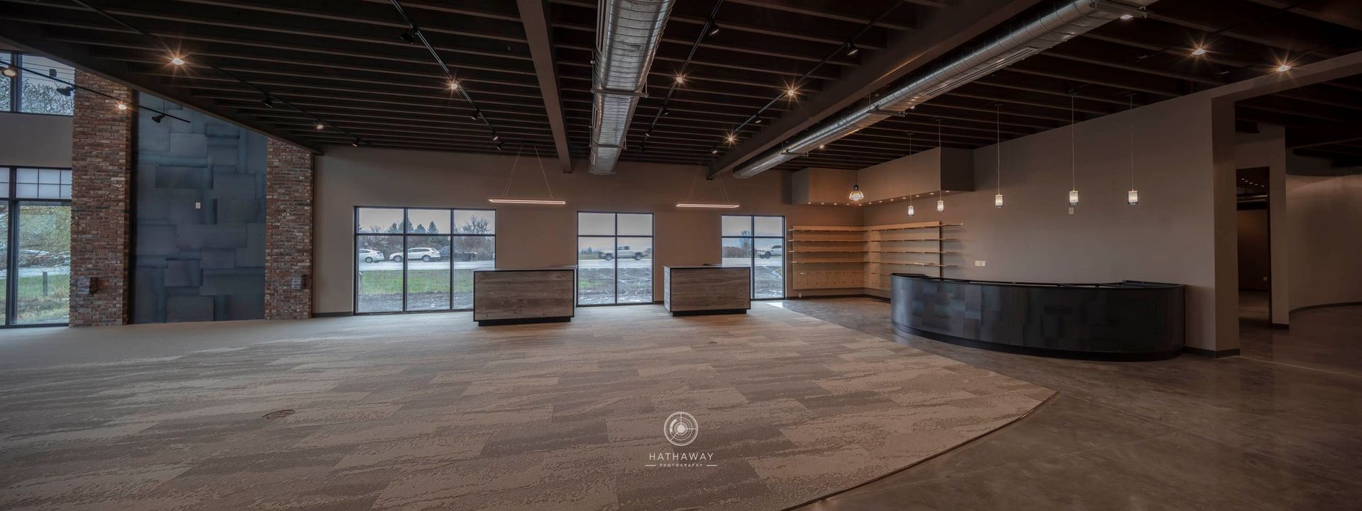 Wide shot of a modern, empty interior space with industrial ceilings, polished concrete floors, and stone pillars.
