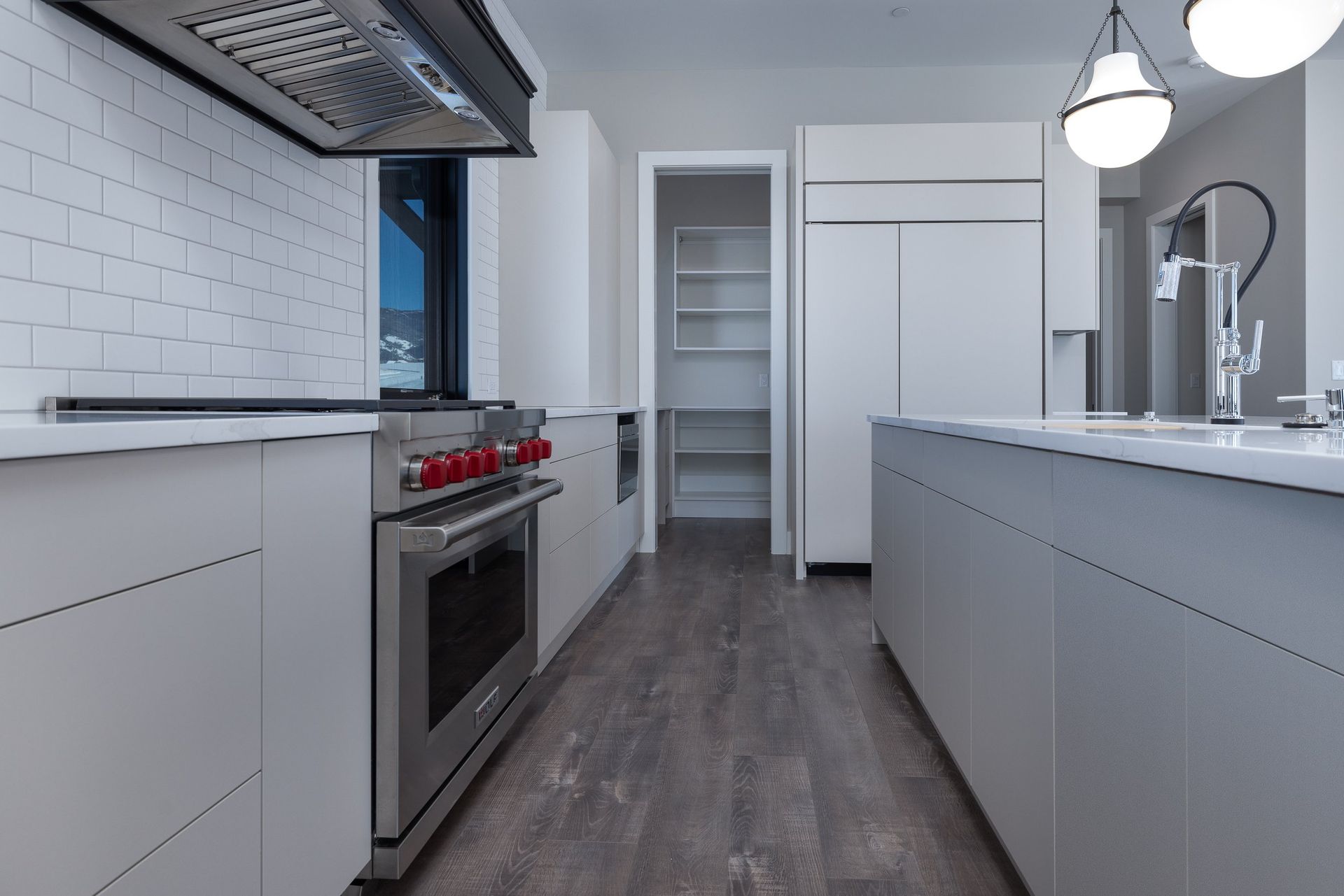 Modern white kitchen with stainless steel appliances, white subway tile backsplash, and a central island.