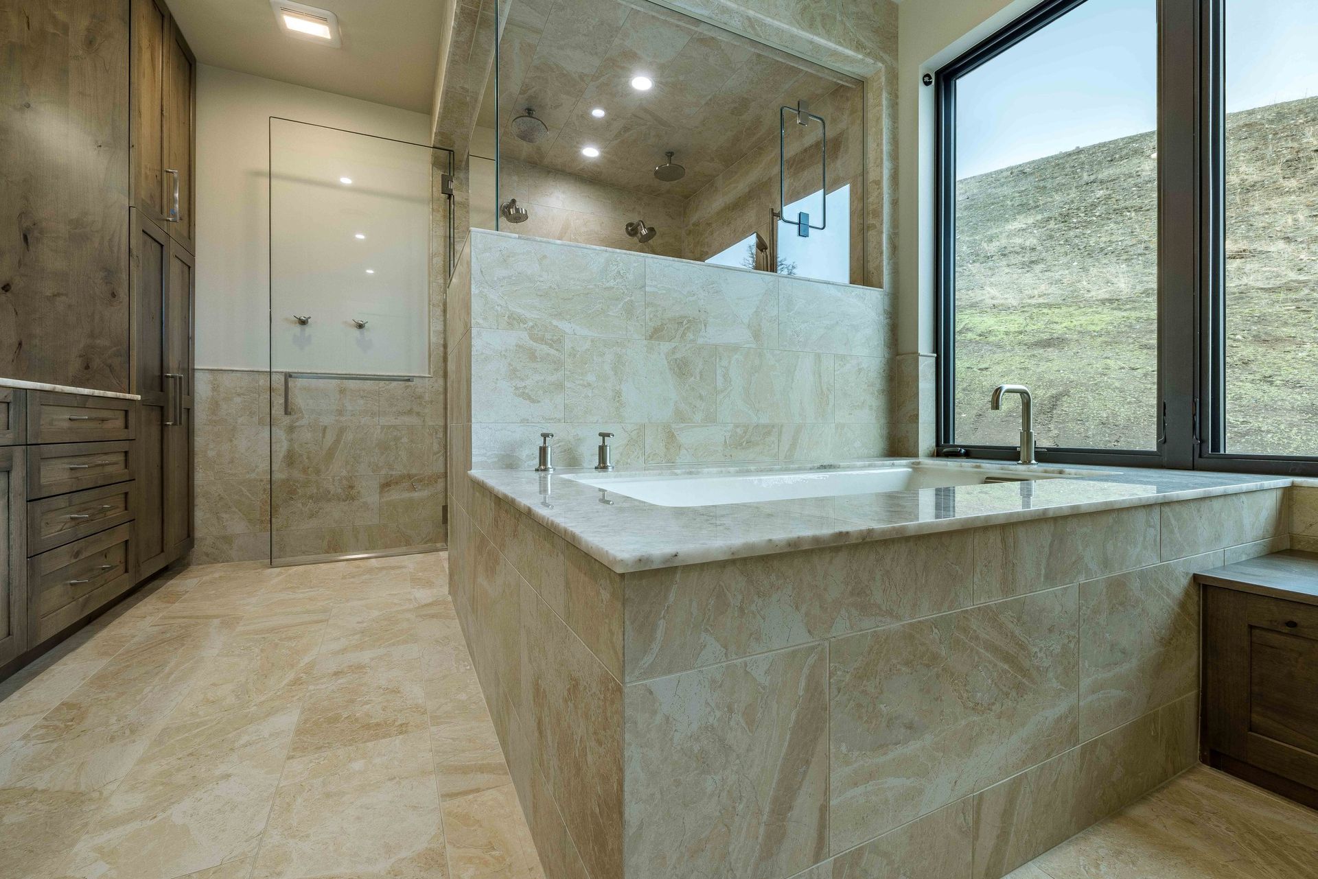 A modern bathroom featuring a stone-tiled soaking tub, a glass-enclosed shower, and dark wood cabinetry.