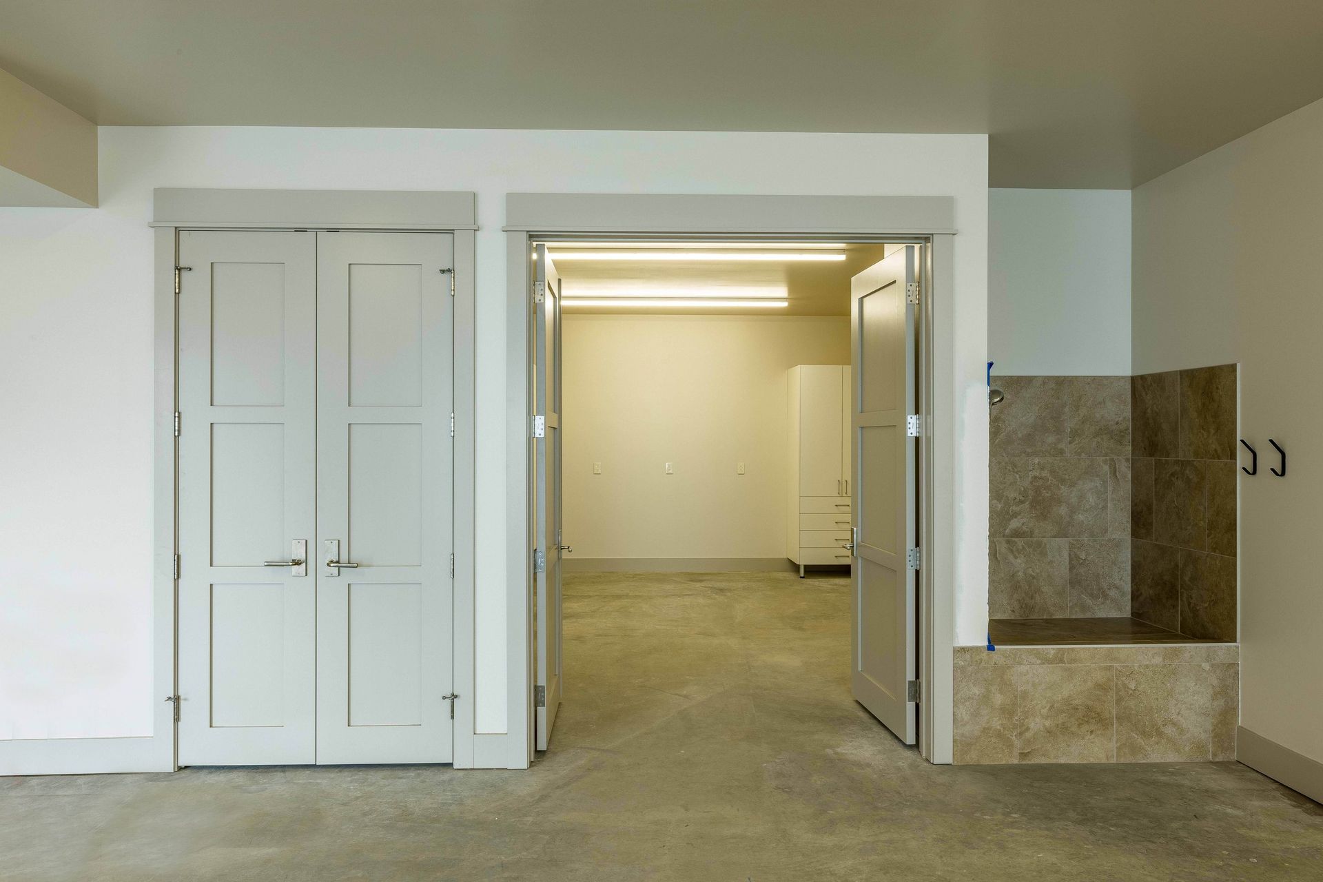A room with double doors, an open doorway into a secondary space, and a tiled built-in bench on the right wall.