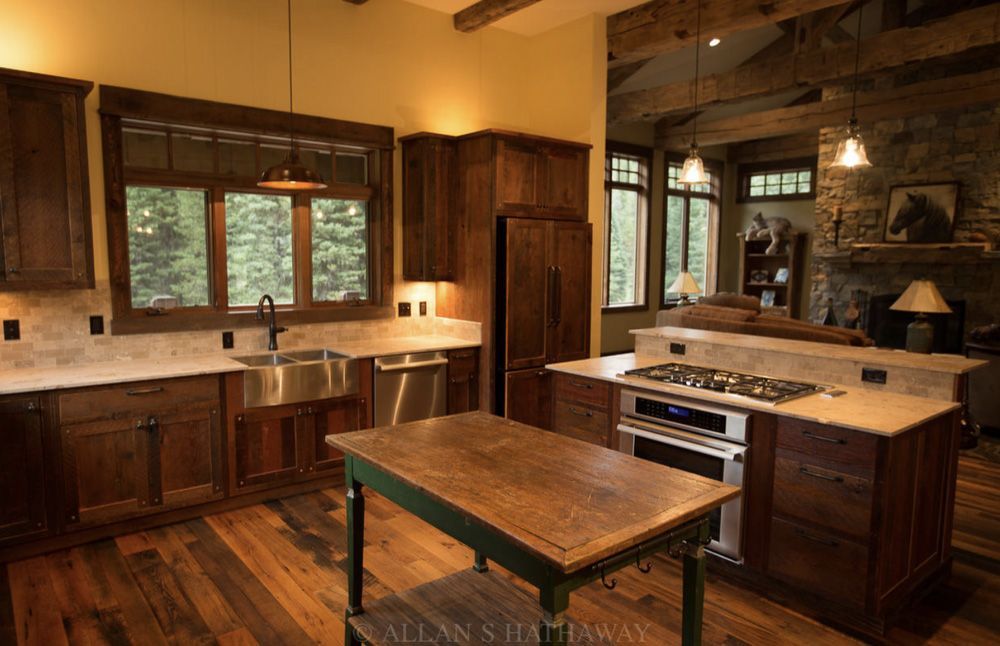 A rustic kitchen with dark wood cabinets, a wooden island, stone backsplash, and an adjacent living area with a fireplace.