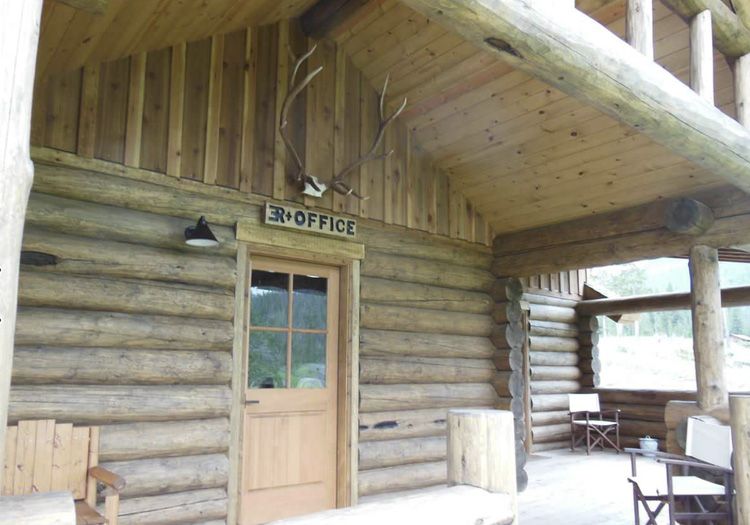 A log cabin porch with a wooden door labeled 