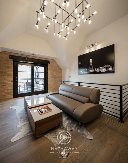 Modern loft living room with beige sofa, nested coffee tables, wooden walls, chandelier, and a large black-and-white art.