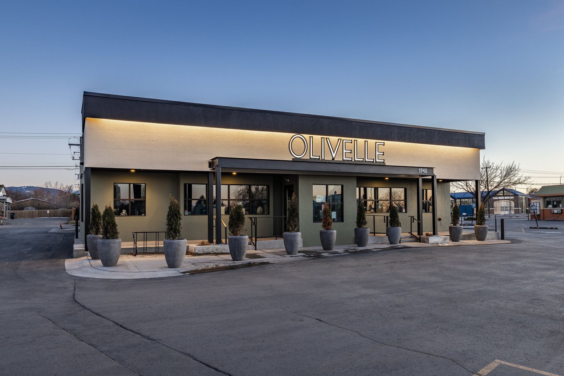 A one-story building with a lit, olive-green exterior and 