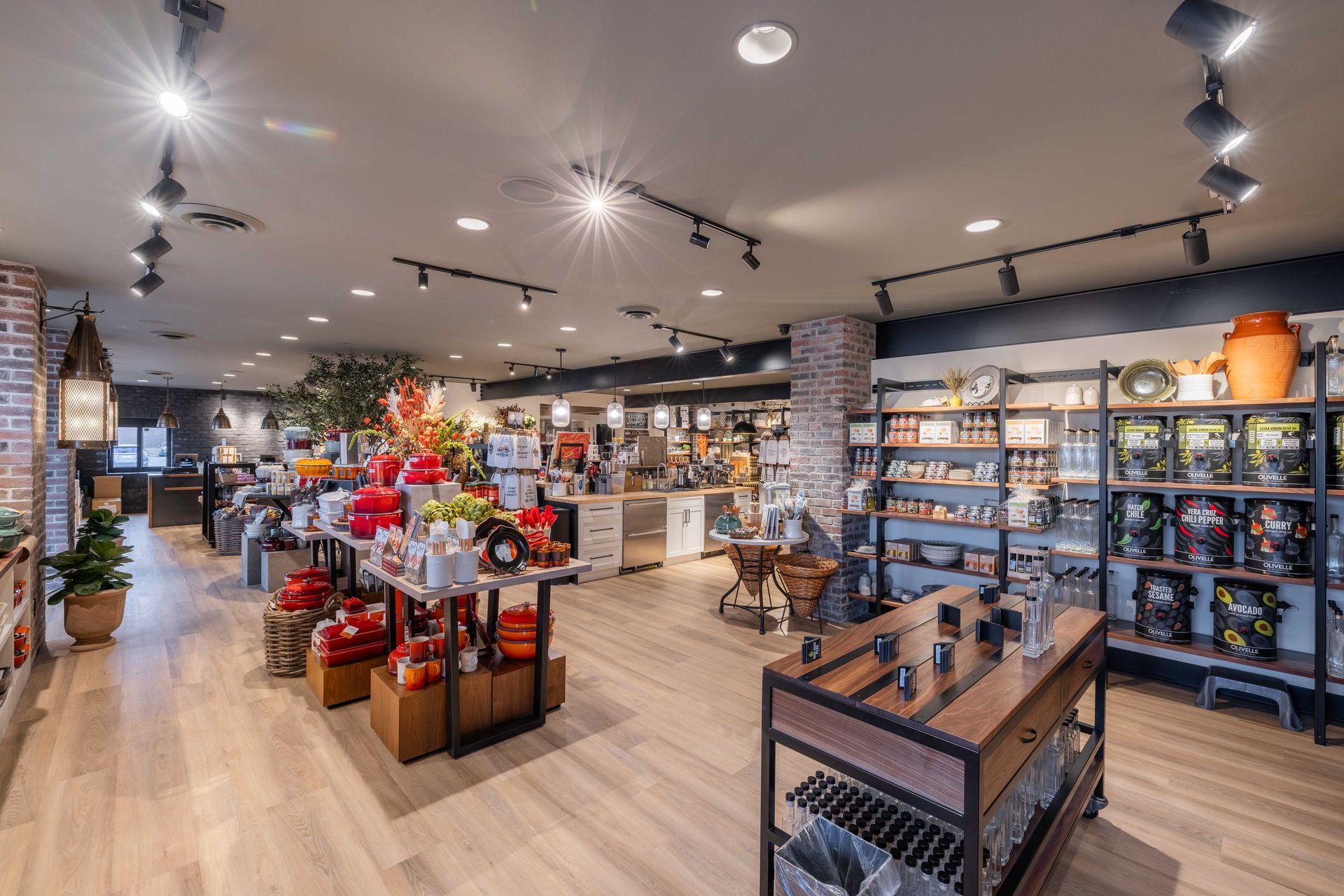 A brightly lit retail shop interior featuring wooden flooring, product display shelves, and tables with red merchandise.