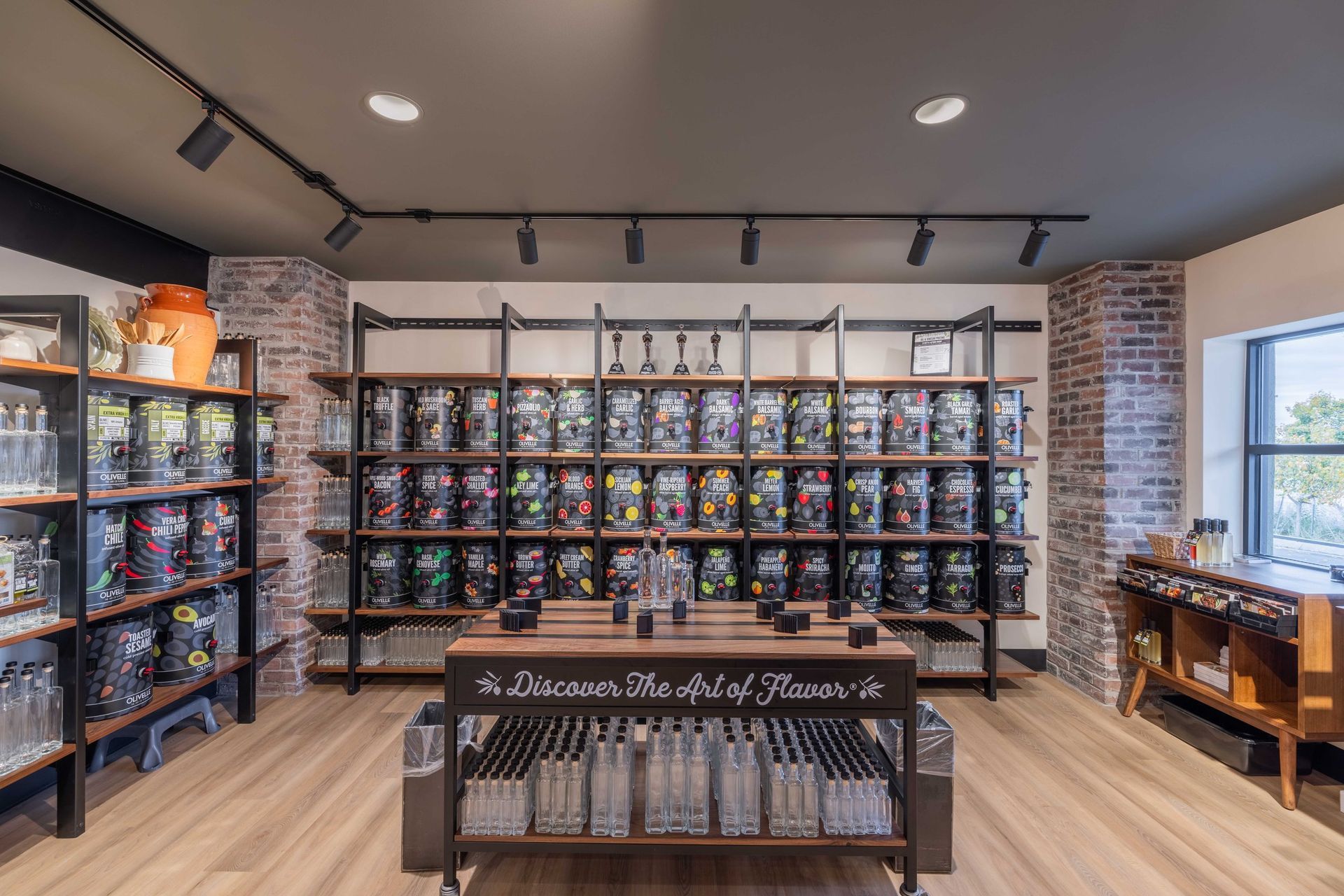 Store interior with shelves of floral products, wooden display tables, wood-look flooring, and industrial lighting.