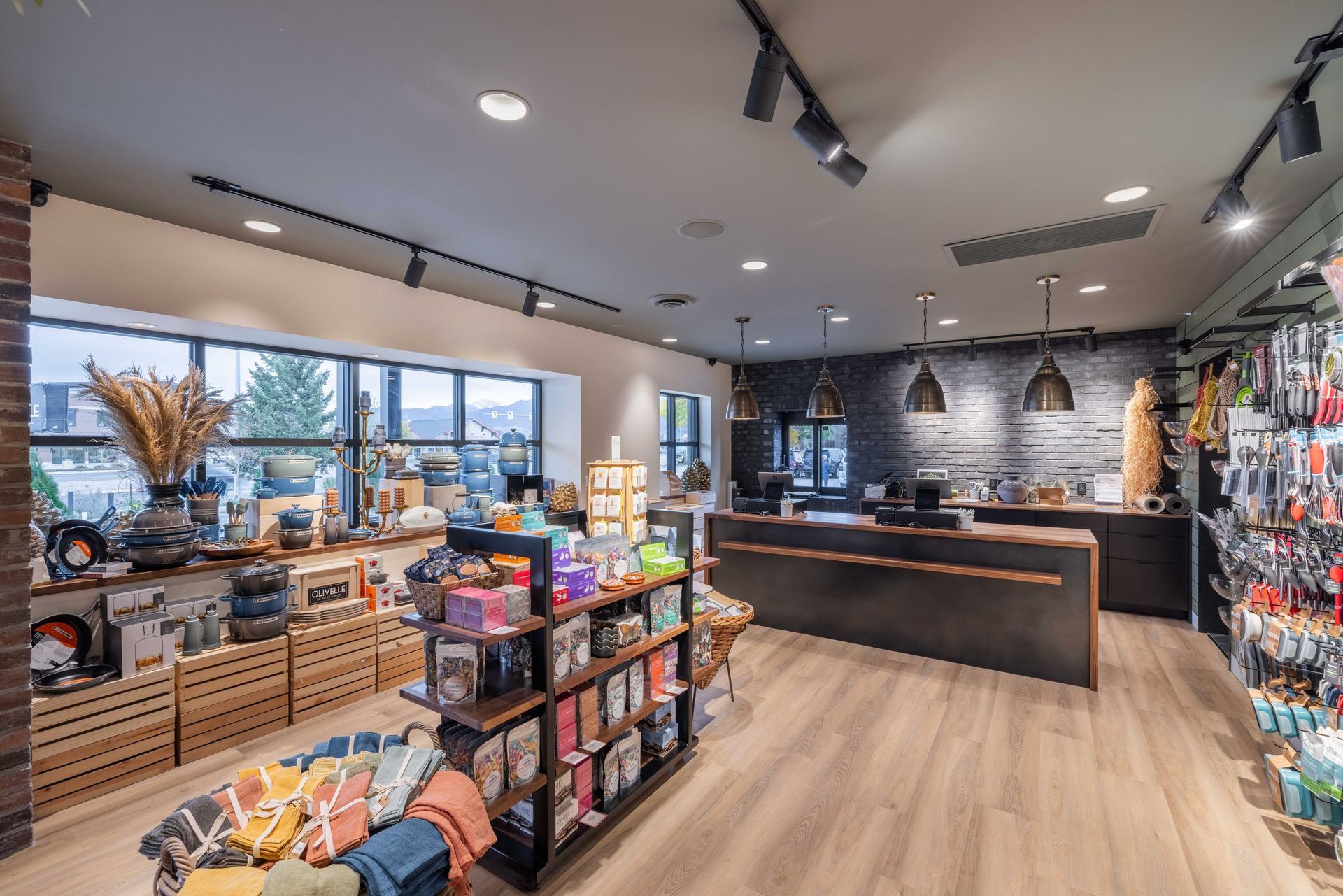 A modern retail store interior featuring wooden shelving, displays of home goods, and a dark service counter.