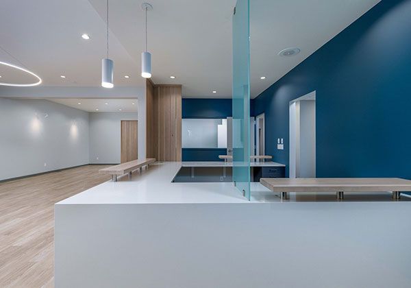 Modern minimalist lobby with blue walls, white counters, wood accents, and polished floors.