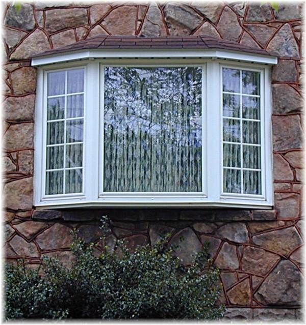 A large bay window on a stone wall