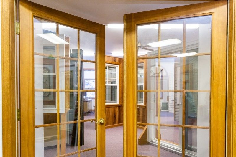 A pair of wooden french doors are open in a room.