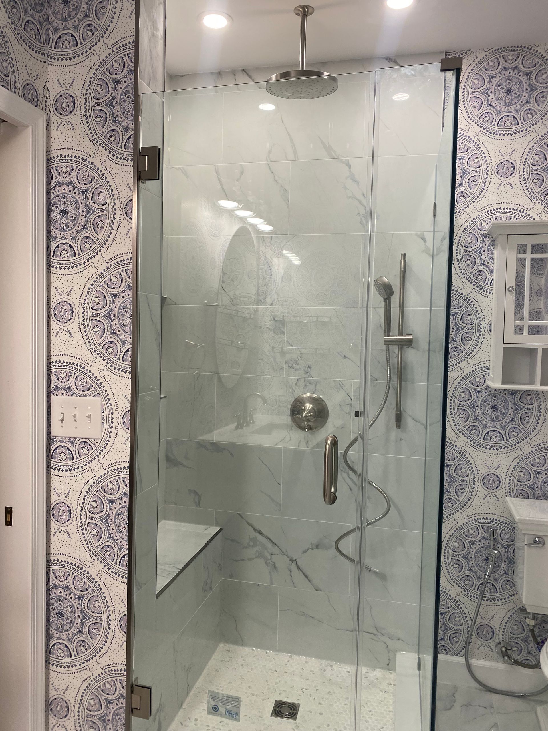 Modern tiled bathroom with a glass shower door, rain shower head, and handheld shower fixture.