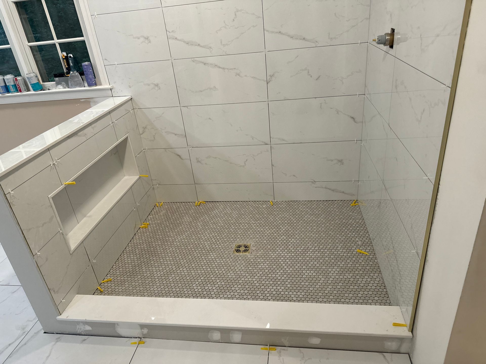 White tiled shower stall with a low threshold and a pebble-style shower floor