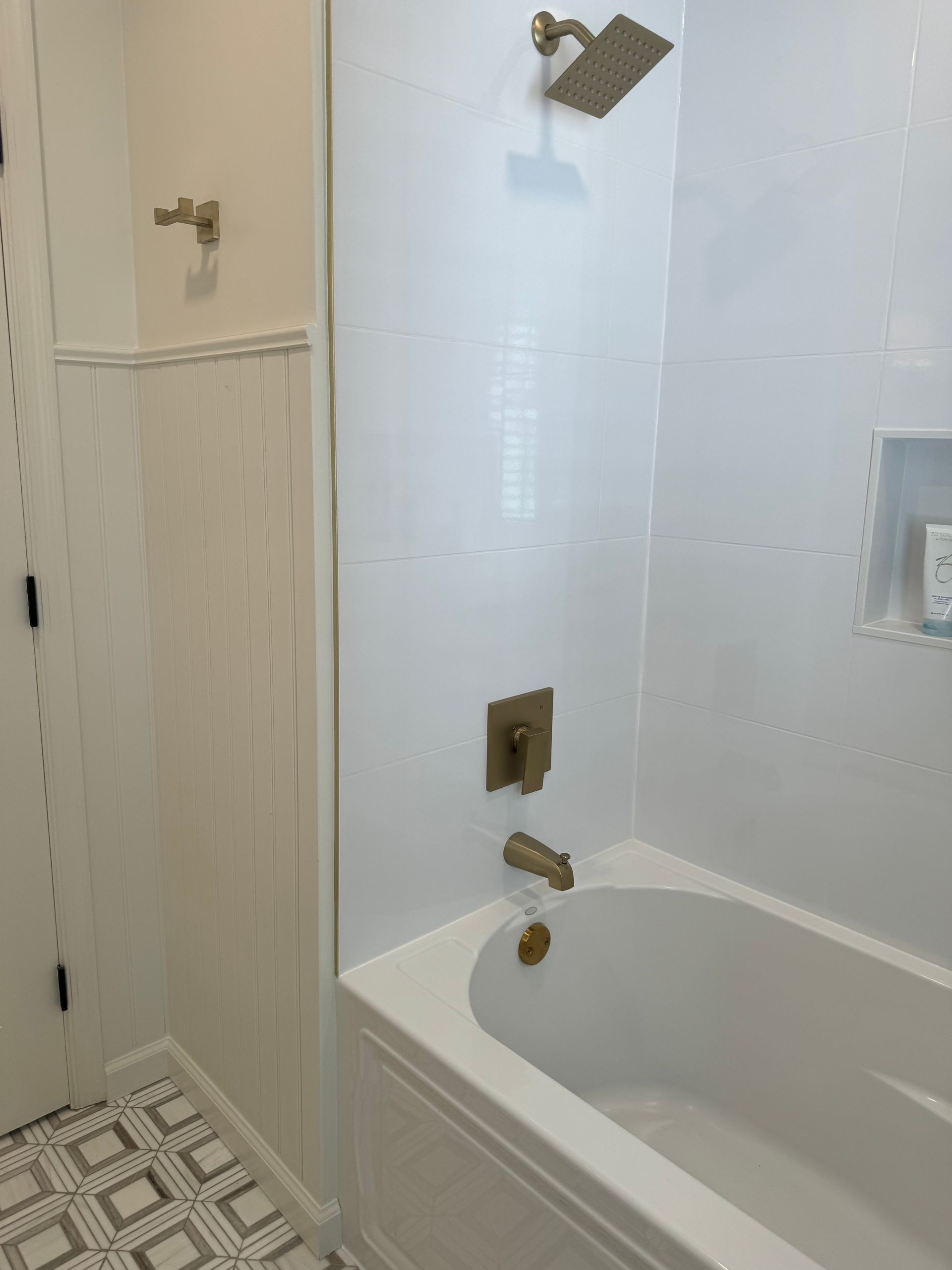 Accessible bathroom with walk-in tub, grab bars, wall-mounted shower head, and tiled walls