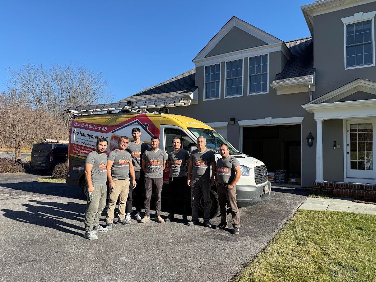 Seven people standing by a red-and-yellow emergency vehicle outside a suburban house