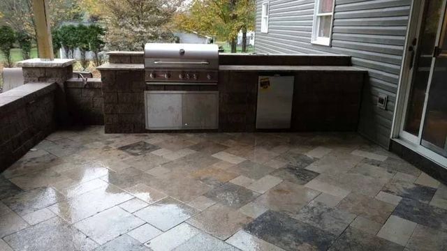 A grill is sitting on a patio next to a house.