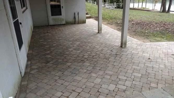 A brick patio with a covered porch and a white door.