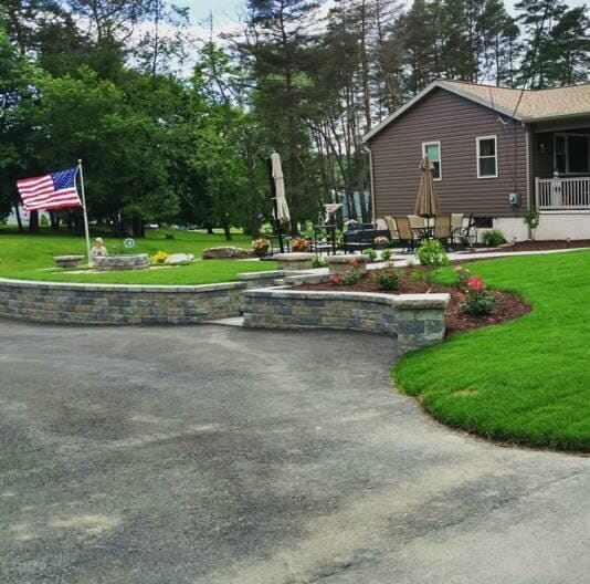 A driveway leading to a house with an american flag in the background