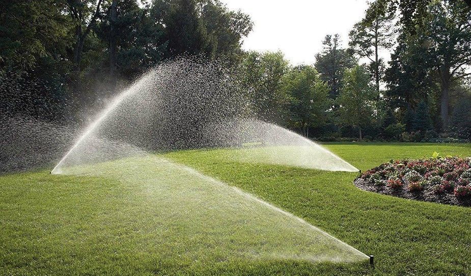 Two sprinklers spraying water on a lush green lawn