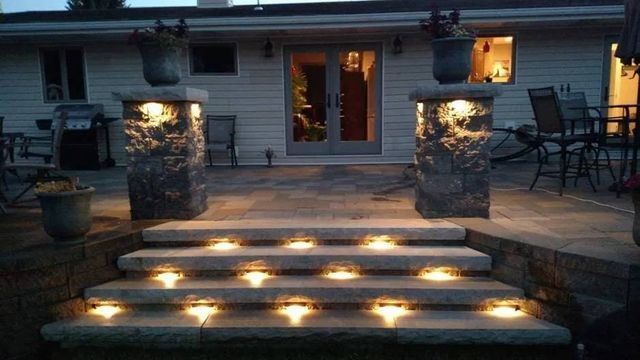 A set of stairs with lights on them in front of a house.