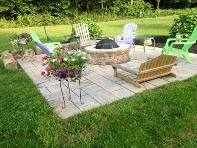 There is a fire pit in the middle of the patio surrounded by chairs.
