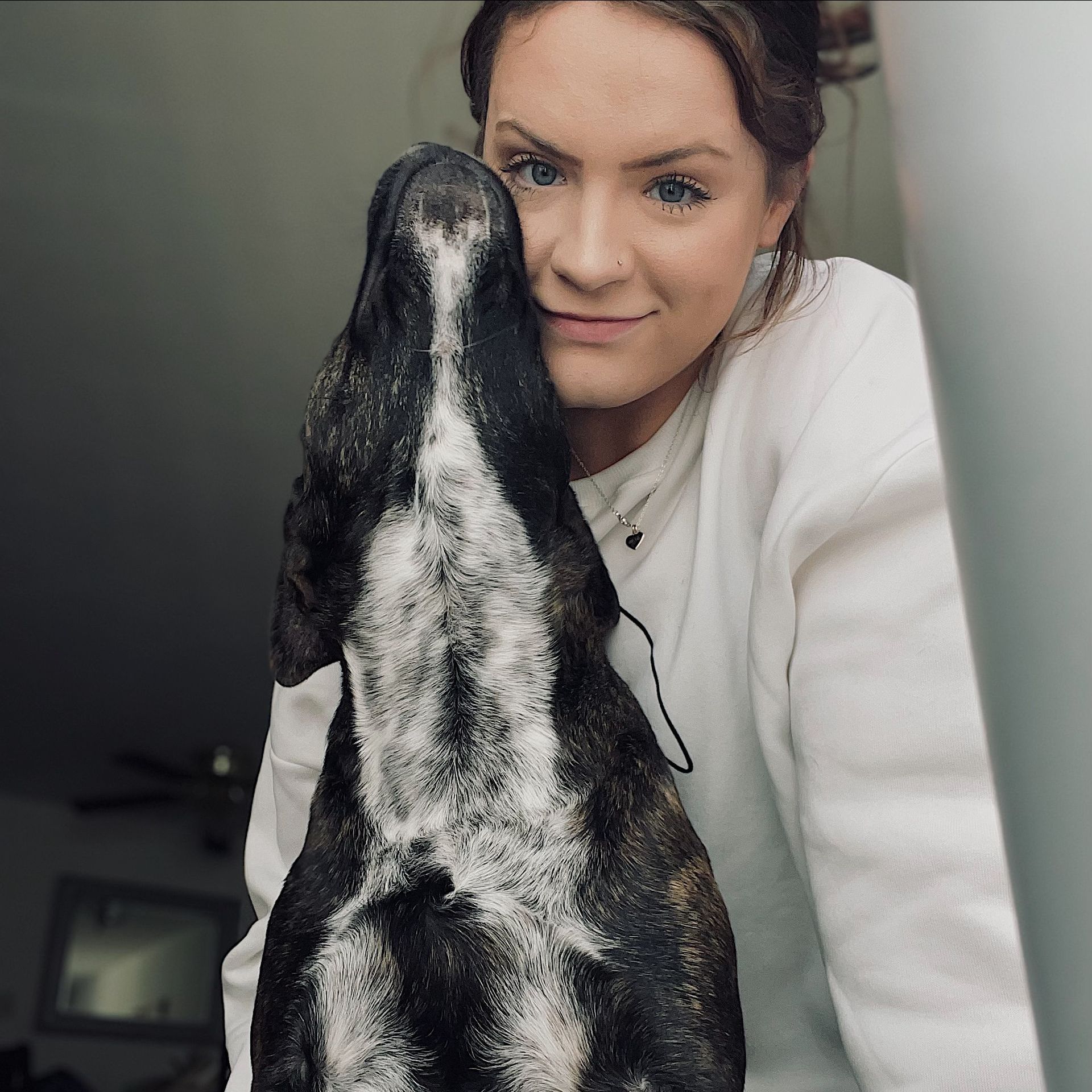A woman is standing next to a brown and white dog