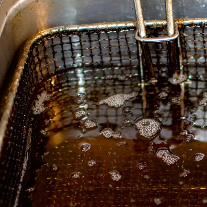 A close up of a frying basket filled with oil.