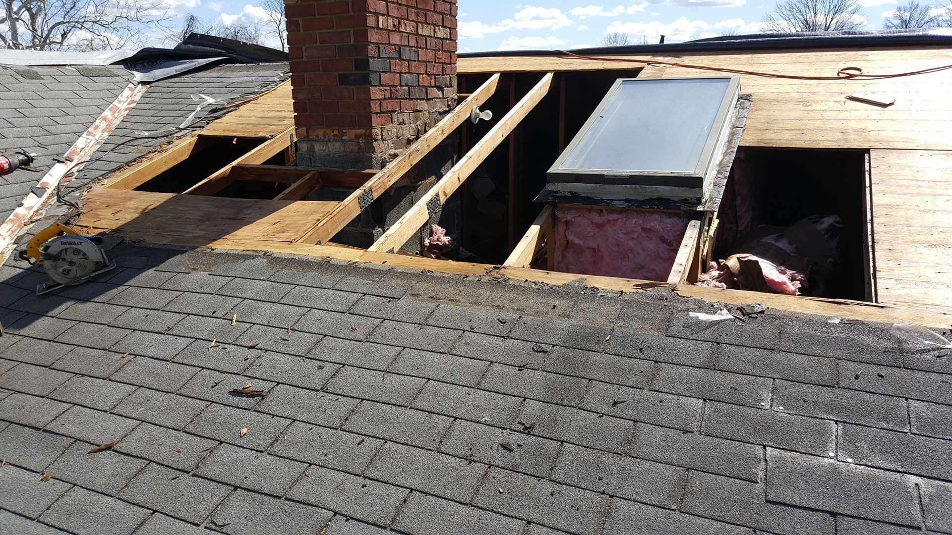 A roof with a chimney and a skylight on it