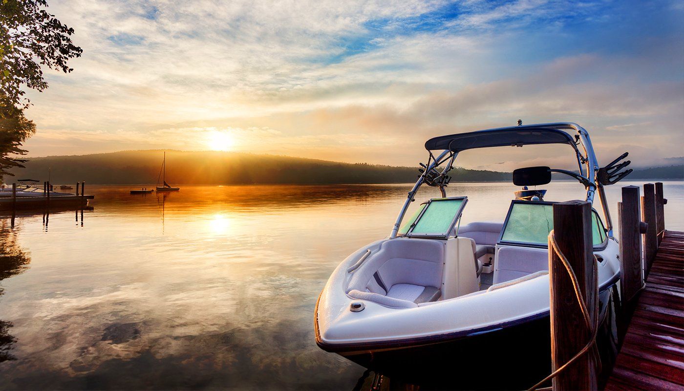 A boat is docked at a dock on a lake at sunset