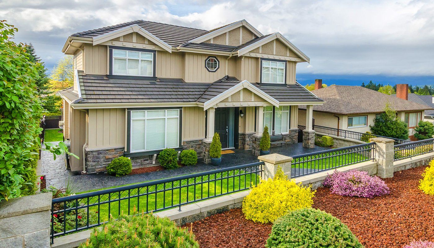 Learn More About Homeowners Insurance A large house with a fence and flowers in front of it