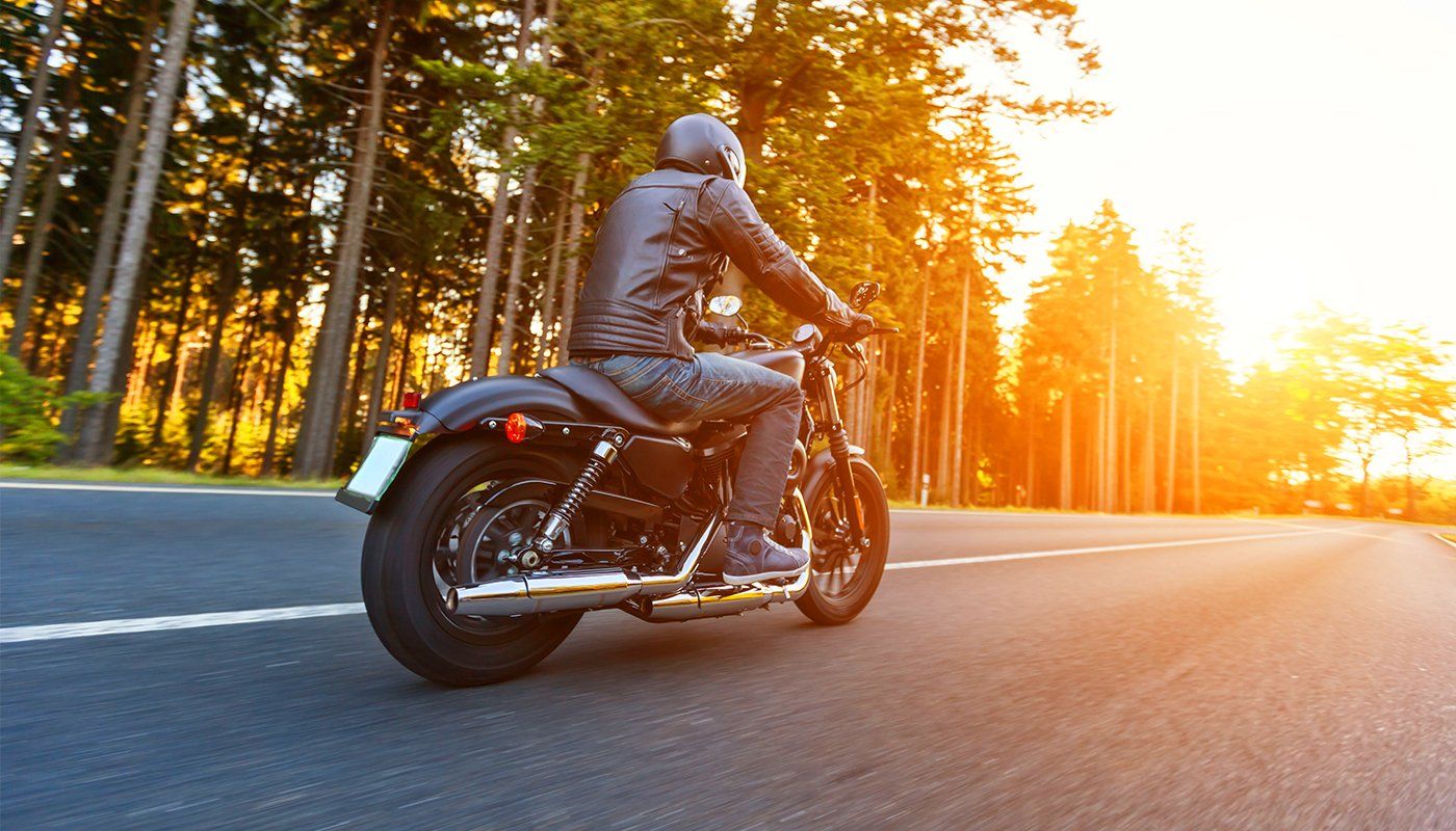 Learn More About Motorcycle/ATV Insurance A man is riding a motorcycle down a road