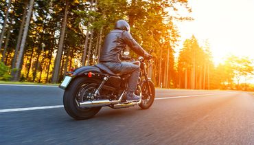 Learn More About Motorcycle/ATV Insurance A man is riding a motorcycle down a road