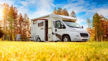 Learn More About RV Insurance A white rv is parked in a field with trees in the background