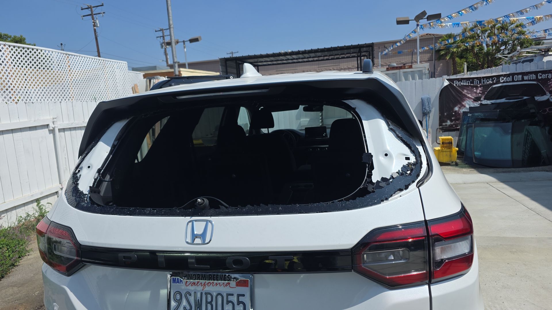 Rear view of a white Honda SUV with a shattered rear windshield, license plate visible, parked outside.