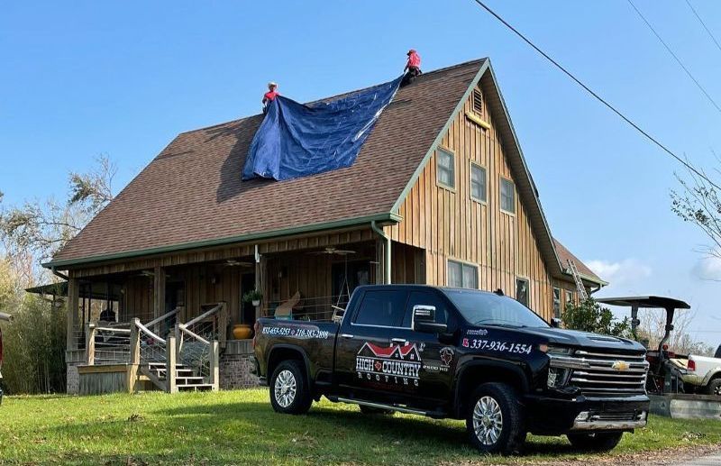 A truck is parked in front of a house with a tarp on the roof