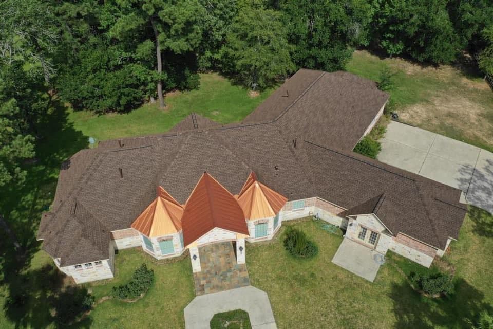 An aerial view of a large house with a red roof surrounded by trees.