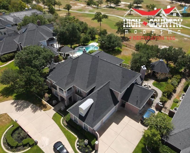 An aerial view of a large house with a black roof