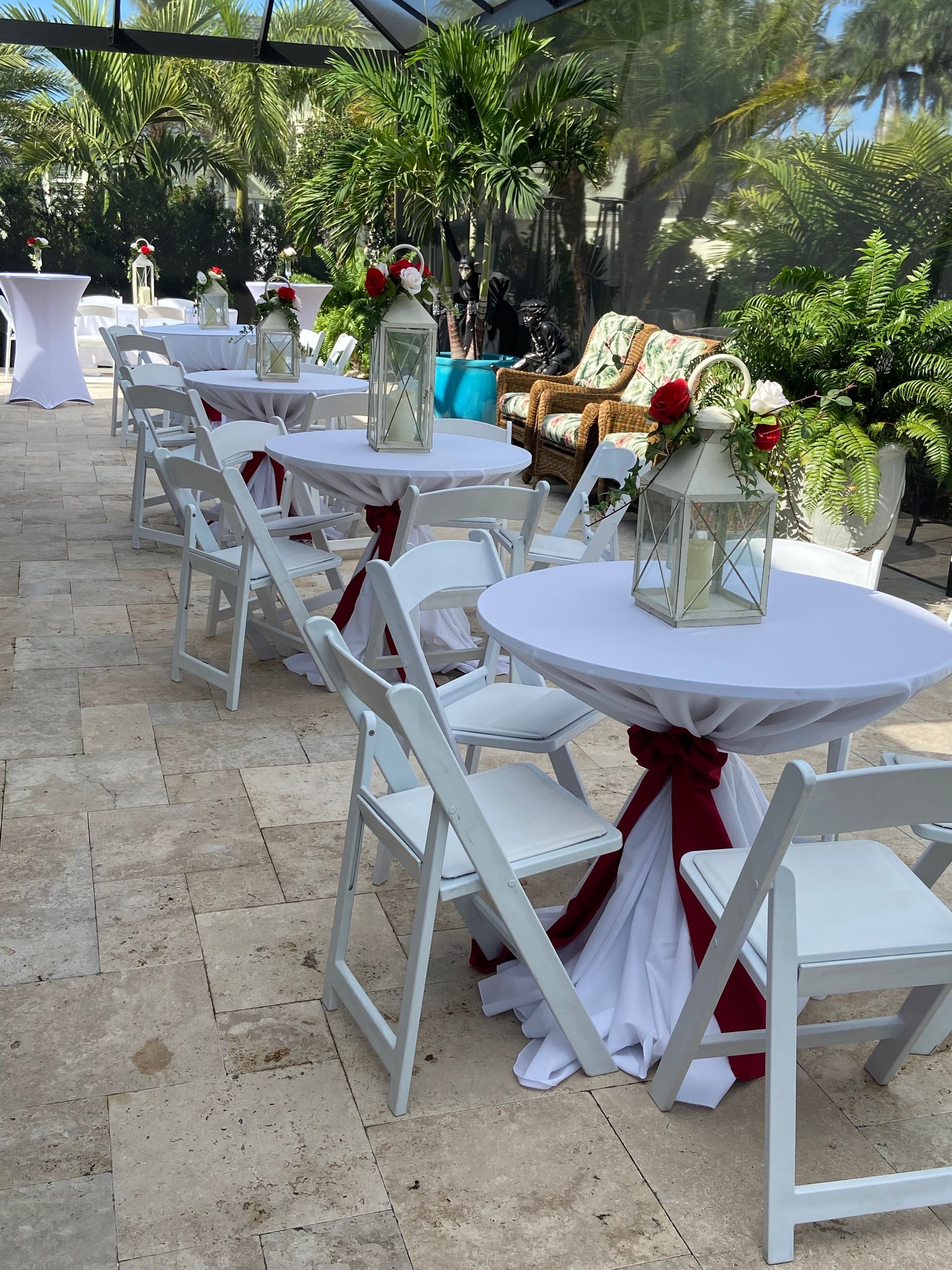 Outdoor event with round white tables draped with white and burgundy fabric