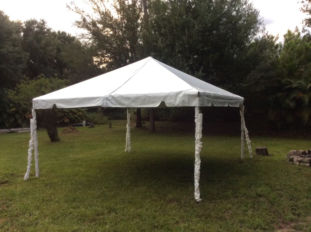 A white canopy tent set up on green grass with trees in the background