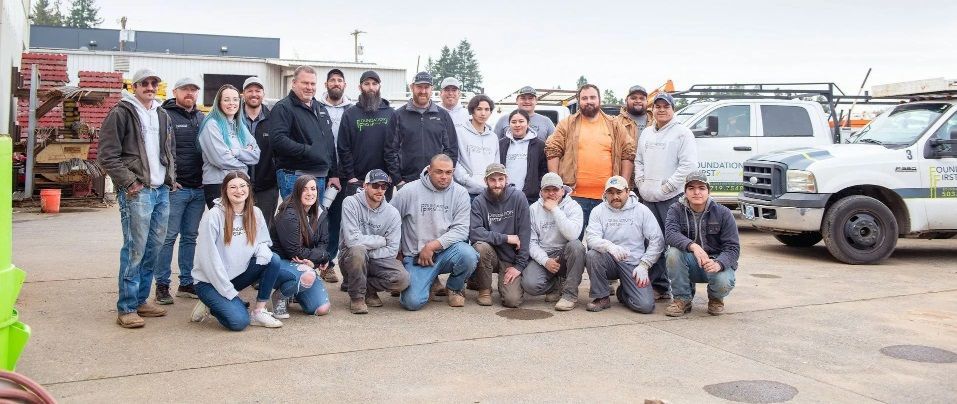 A large group of people are posing for a picture in front of trucks.