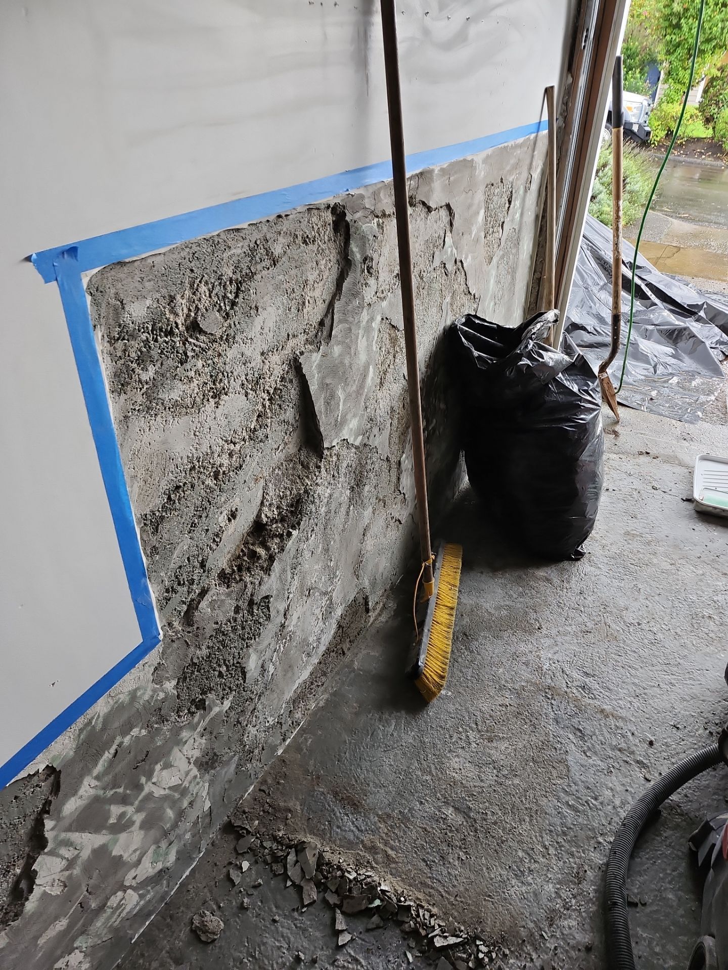 A broom is sitting on the ground next to a wall.