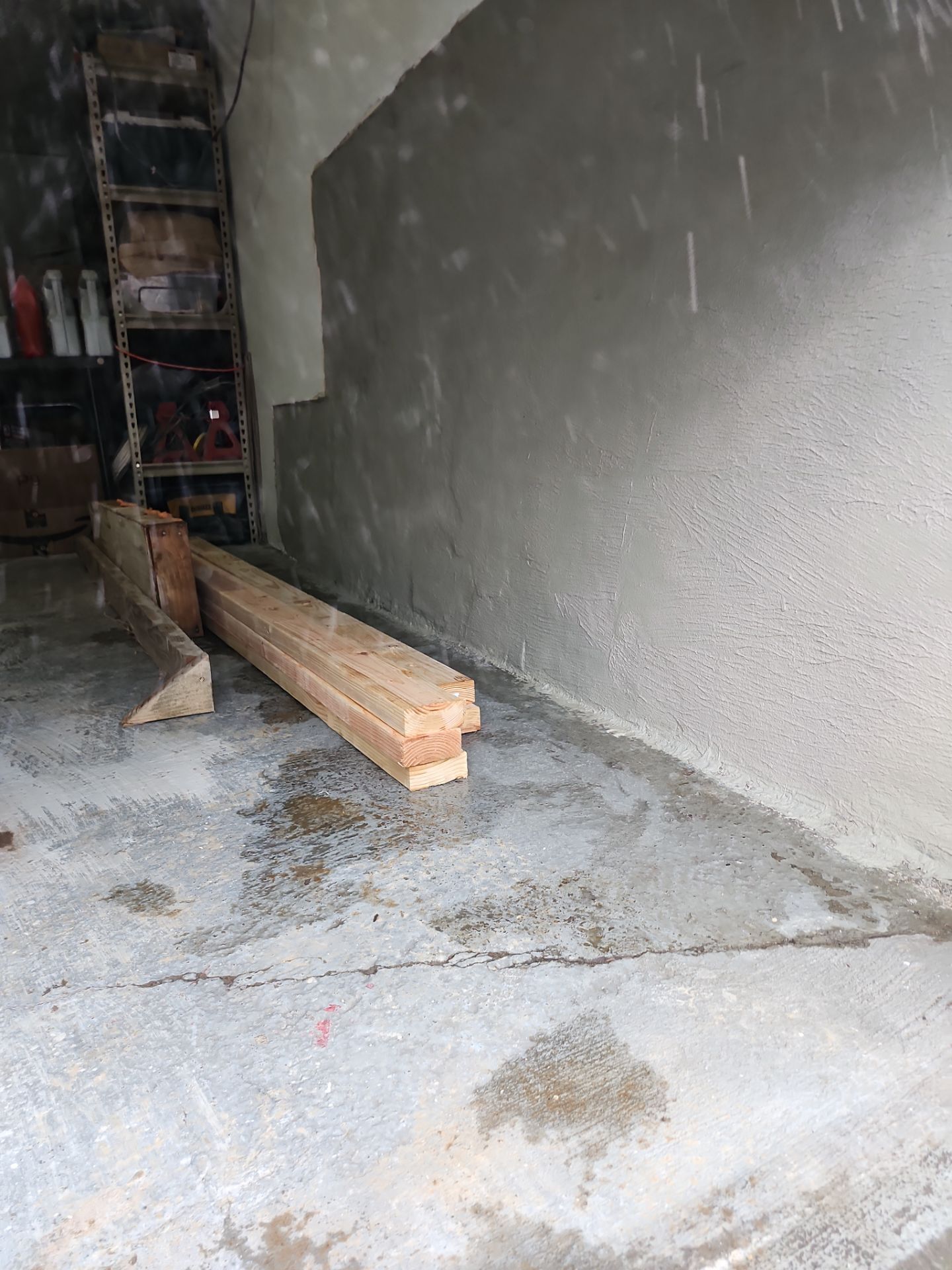 A pile of wood is sitting in a garage next to a ladder.