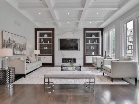 Living room with white furniture, fireplace, bookshelves, and large windows.