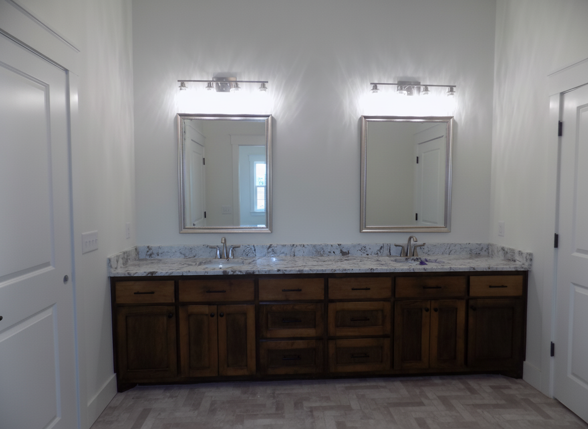 Bathroom with two sinks, dark brown cabinets, granite countertop, and two mirrors with lights.