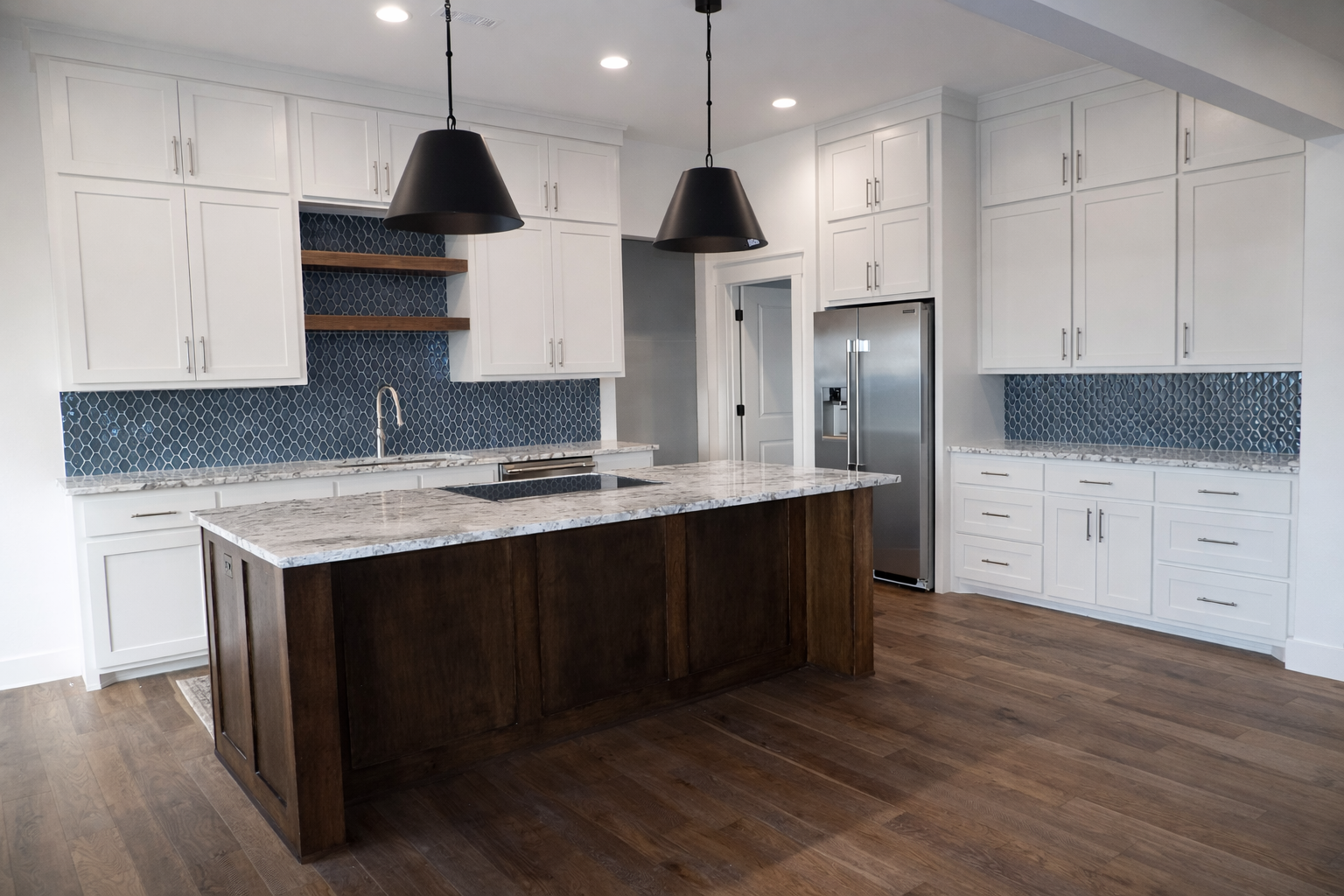 Modern kitchen with white cabinets, dark wood island, blue tile backsplash, and stainless steel appliances.