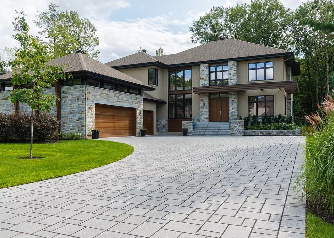 Large modern house with gray stone accents, brown garage door, and patterned driveway.